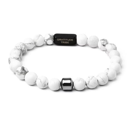 White beaded bracelet with a black tag labeled 'Gratitude Tribe' on a white background, white, black, front.